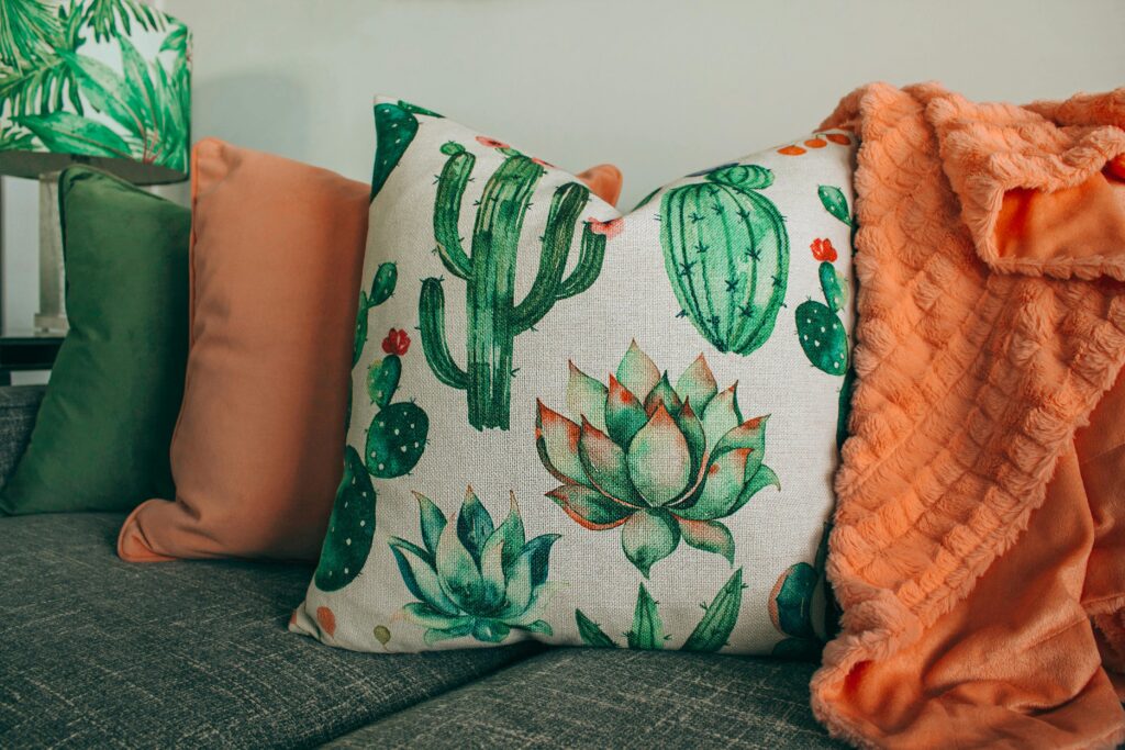 A stylish living room setup with cactus-themed pillow and soft orange blanket.